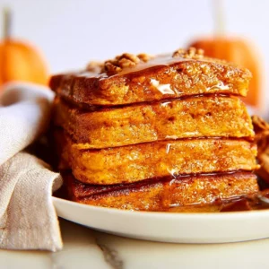 Fluffy pumpkin spice sheet pan pancakes topped with syrup and whipped cream